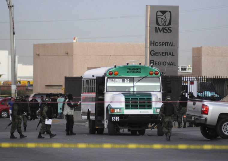 Image: Soldiers and forensic workers stand around bus parked outside a hospital in Ciudad Juarez