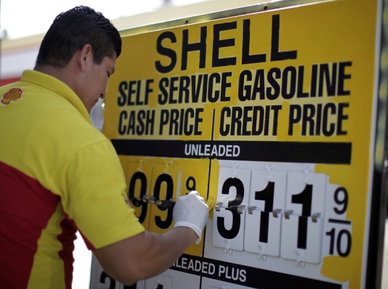 Image: A man paints a price sign at a gas station in Los Angeles
