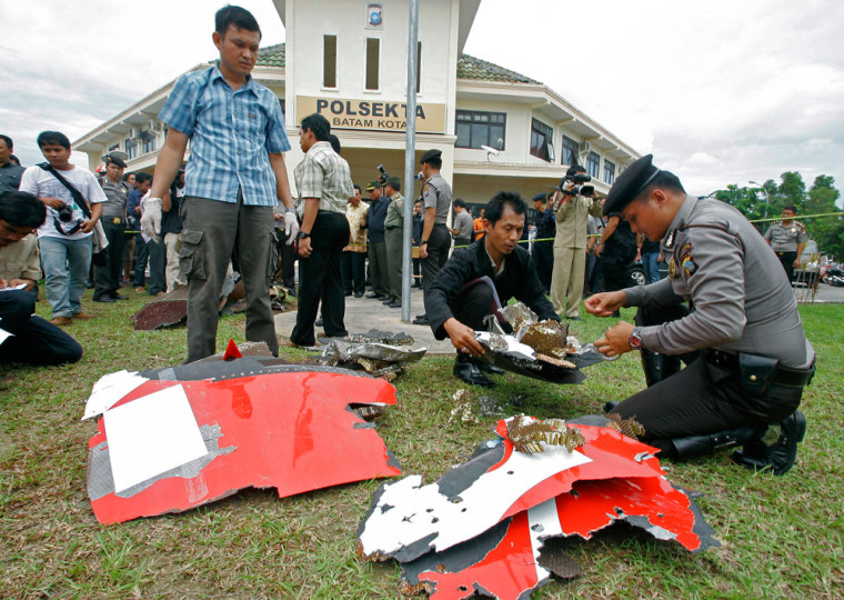 Image: Indonesian police officers inspect parts of a Qantas jetliner that were found in the area, at the local police headquarters in Batam, Indonesia.