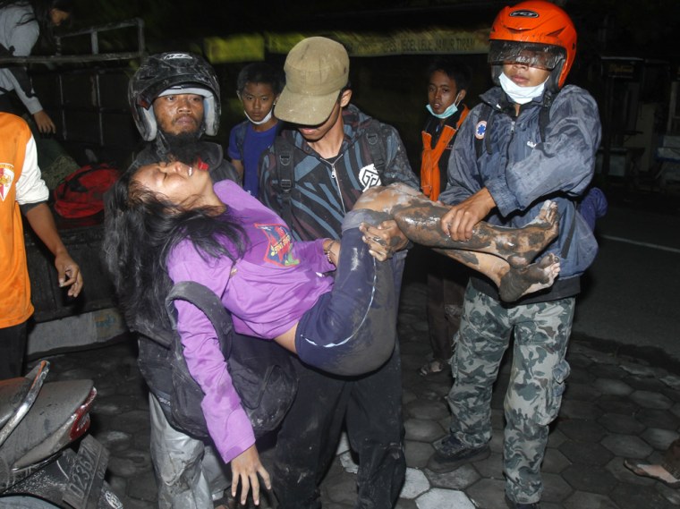 Image: Villagers carry a women as they flee their homes following another eruption of Mount Merapi
