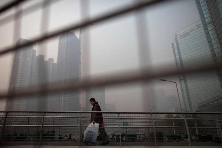 Image: A man walks on a pedestrian overpass on a hazy day at Beijing's Central Business District, China