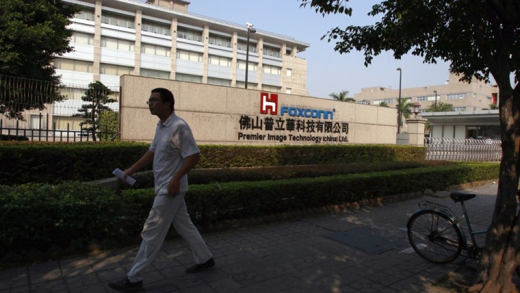 Image: A Foxconn worker walks past a factory belonging to affiliate Foxconn Premier Image Technology (China) Ltd in Foshan in Guangdong province, southern China