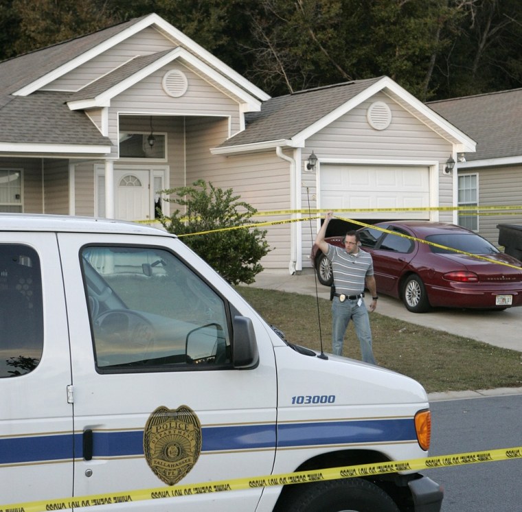 Image: A Tallahassee investigator lifts police tape to pass under at a home