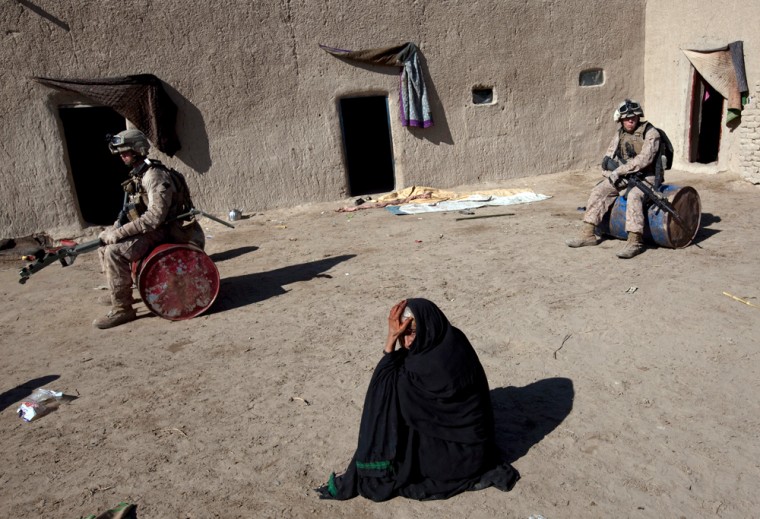 Image: An Afghan woman waits as U.S. Marines rest during a search of her residence in the Garmsir district of Helmand Province
