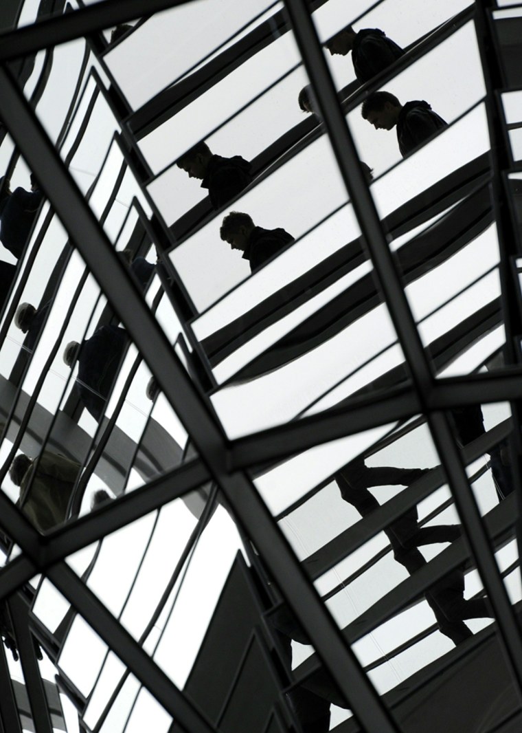 Image: Visitors are reflected in mirrors in the glass dome of the Reichstag building