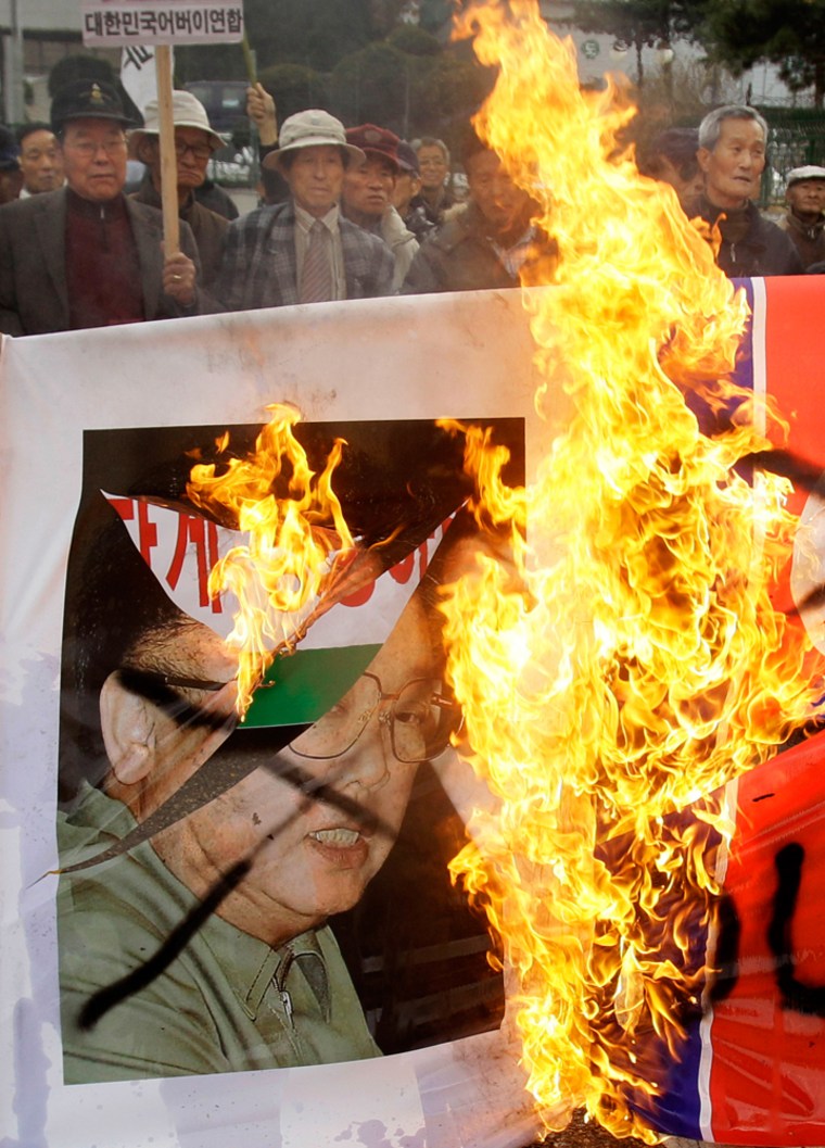 Image: Protesters burn portraits of North Korea leader Kim Jong Il and the national flag in front of the Defense Ministry