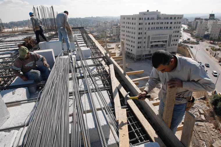 Image: Palestinian labourers work on top of a building under construction in  Ramallah