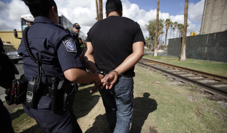 Image: An unidentified man is detained for unknown reasons by customs officials at the port of entry along the US-Mexico border in Calexico, Calif.
