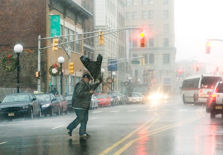 Image: A man's umbrella flips from the strong wind as he crosses Sip Avenue  in Jersey City, N.J.