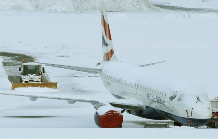 Image: A snow plough passes a snow covered aeroplane at Edinburgh Airport, in Edinburgh