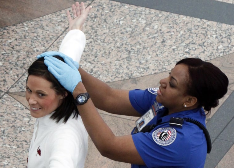 Image: A TSA worker runs her hands over the head of a traveler during a patdown search at Denver International Airport, the day before Thanksgiving