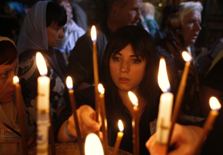 Image: A worshipper lights a candle in the Church of the Nativity in Bethlehem