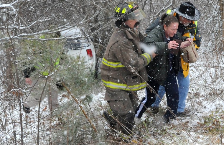 Image: Emergency workers help a woman from her vehicle after if slid off the road on I-40 West near Black Mountain, N.C.