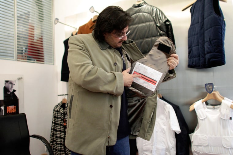 Image: Javier Di Carlo, spokesperson for the Miguel Caballero company which specializes in the sale of protective clothing, shows how armored plates fit into a coat in Mexico City