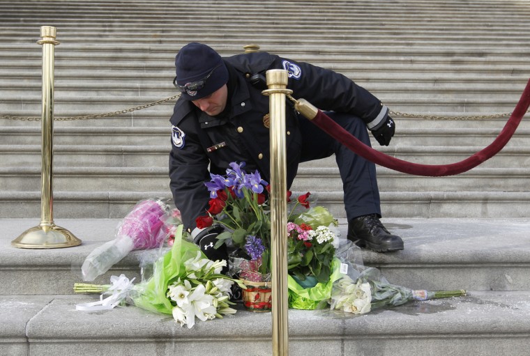 Image: A Capitol policeman arranges flowers placed on the steps of the U.S. Capitol for Arizona Congresswoman Gabrielle Giffords, in Washington