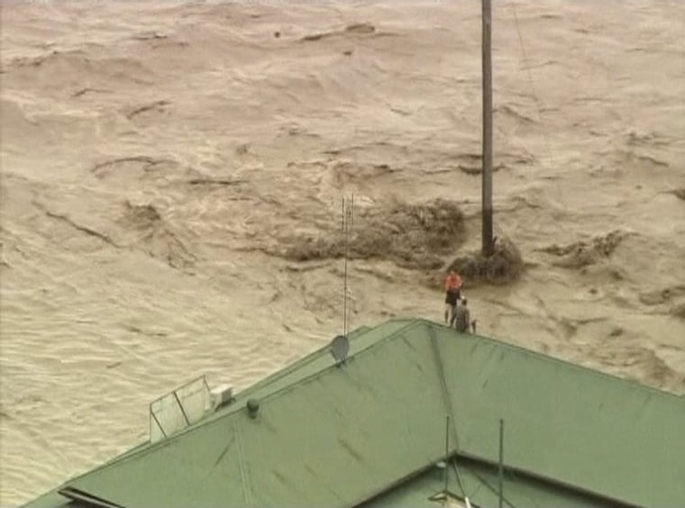 Image: People are seen on the roof of a house in the flooded town of Toowoomba