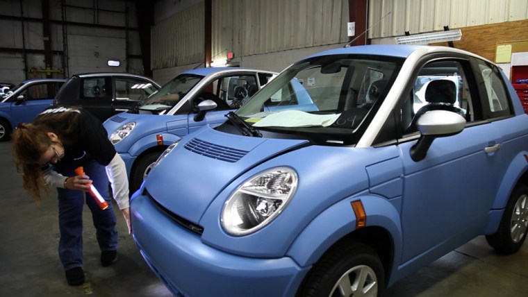 Image: Woman inspects Think electric car