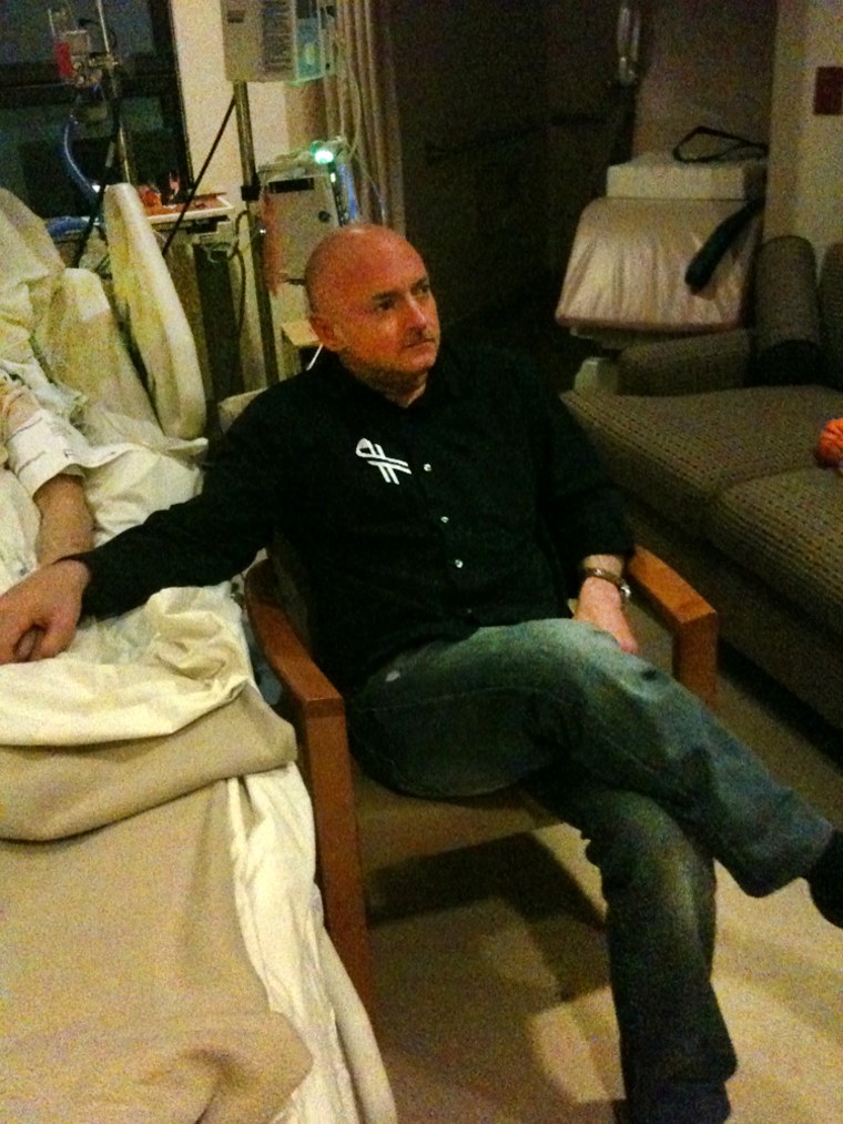 Astronaut Mark Kelly holds the hand of his wife, Rep. Gabrielle Giffords, D-Ariz., in her Houston hospital room Tuesday as they watch the State of the Union speech.