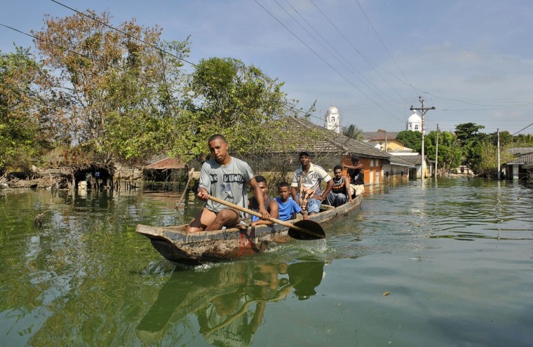 Image: Residents are transported by canoe along a flooded street in Manati, Atlantico province