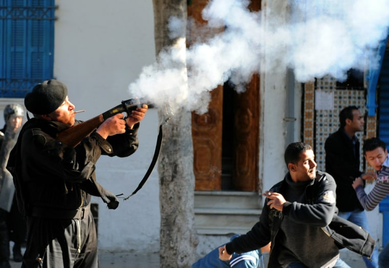Image: A police officer fires a tear gas canister in Tunis