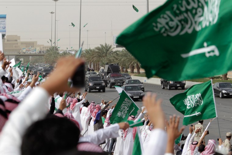 Image: Saudis wave and cheer to welcome the convoy of the King Abdullah of Saudi Arabia as he passes them from the Airport and through the streets of Riyadh