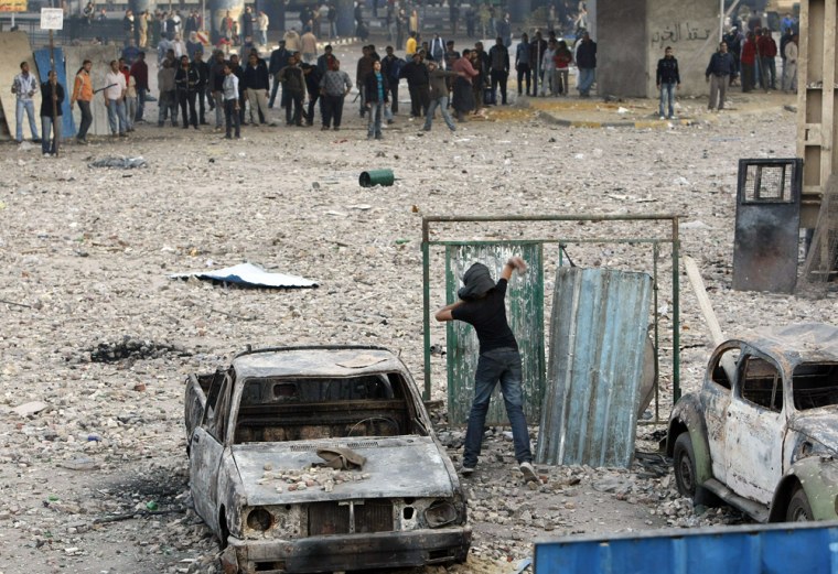 Image: An Egyptian anti-government demonstrator throws a projectile at pro-regime opponents