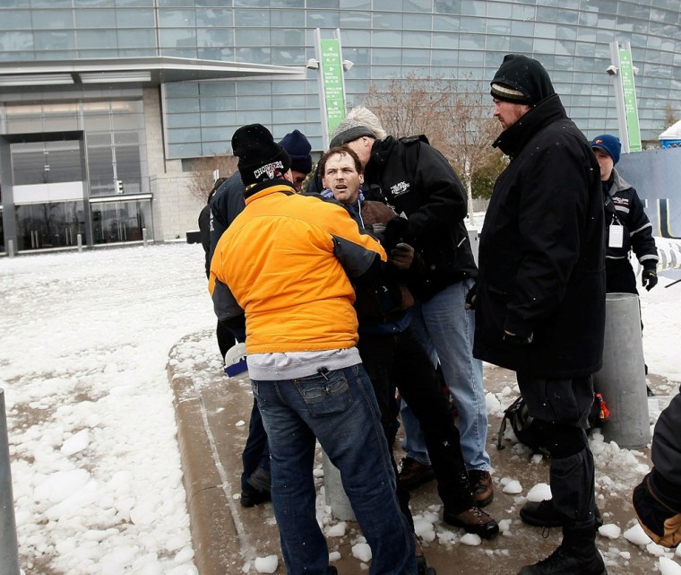 Image: A man is brought to his feet after getting hit by ice that fell from the roof of Cowboys Stadium