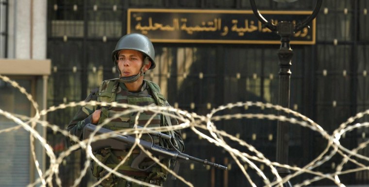 Image: An army soldier stands guard behind a wire fence cordon outside the interior minister's office in Tunis