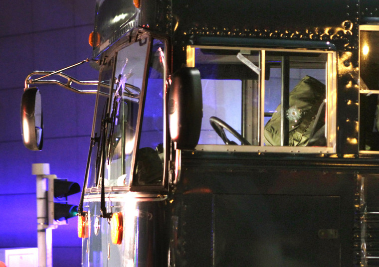 Image: A bullet hole is seen in the driver's window as the bus is towed away after a gunman fired shots at U.S. soldiers