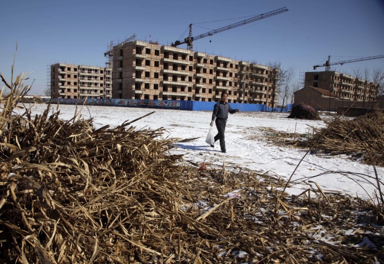 Image: A Chinese farmer walks past the half completed apartment blocks built to relocate the farmers from Damazizhuang village in northern China's Hebei province