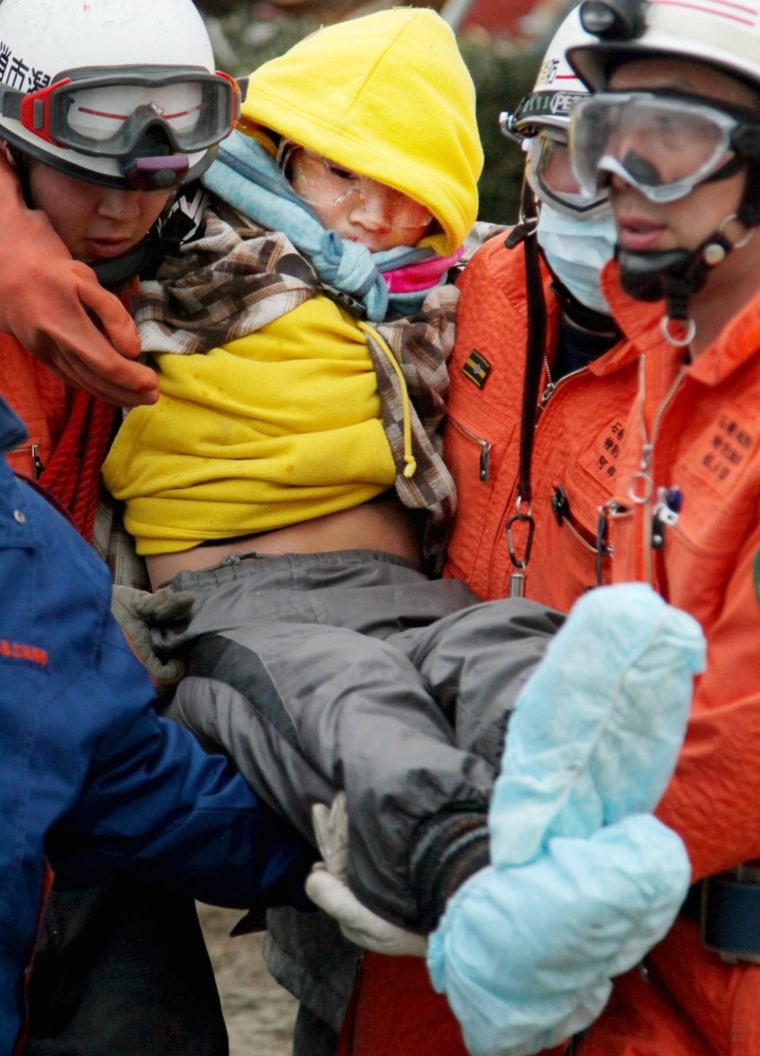 Image: Sixteen-year-old Japanese Jin Abe is carried by rescue workers from the rubble in Ishinomaki