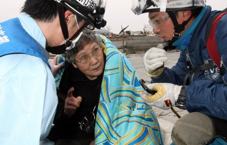Image: Eighty-year-old Sumi Abe is wrapped in a blanket after being rescued from the wreckage of her home for nine days