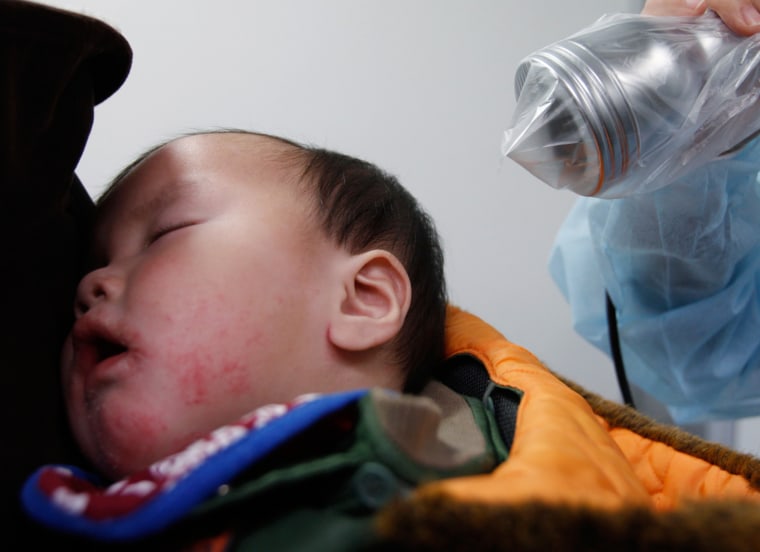 Image: A baby undergoes a screening test for signs of nuclear radiation as he sleeps on his mother's back at a health center in Yonezawa