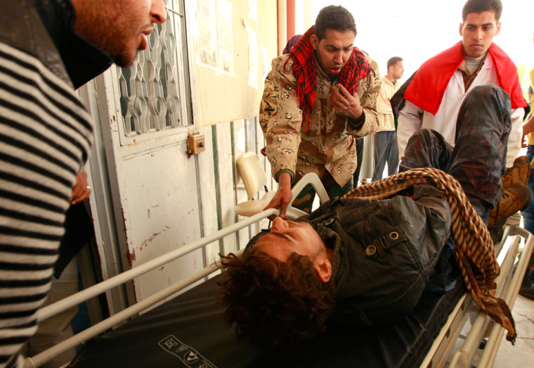 Image: A wounded rebel fighter lies on a stretcher as he is wheeled into the hospital in Ajdabiya
