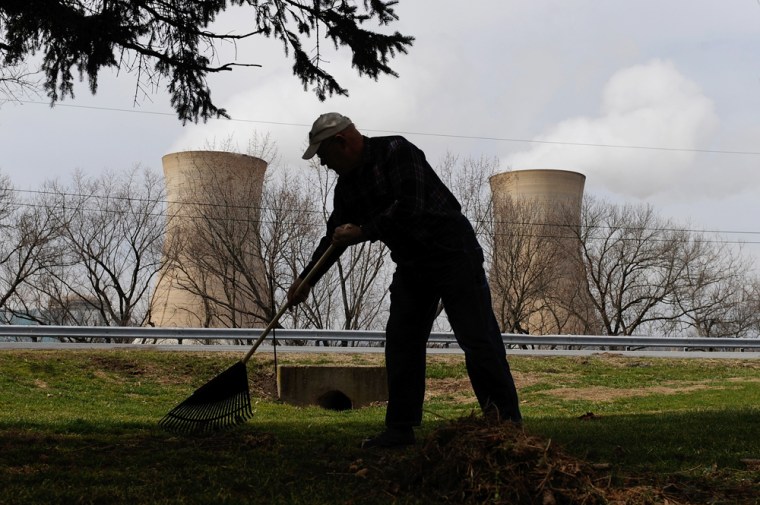 Image: A man rakes his son's front yard across from the Three Mile Island nuclear power plant