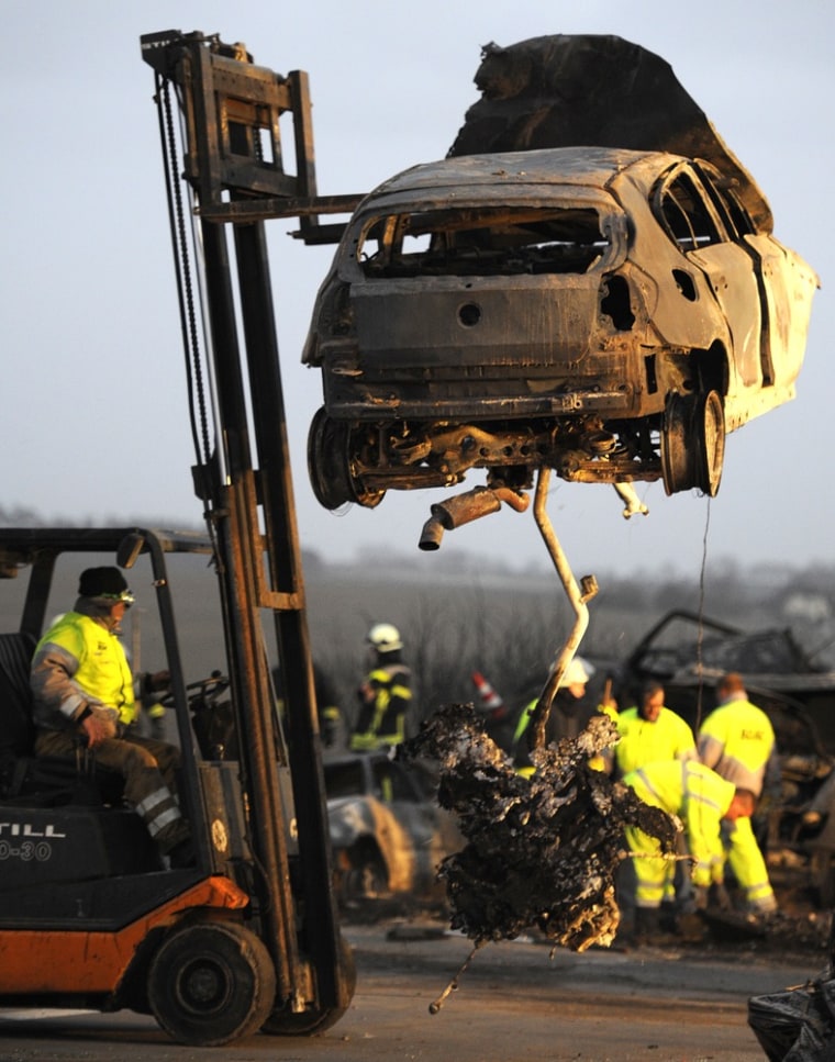 Image: A worker moves a burnt out car on the motorway A 19 near eastern German village of Kavelstorf