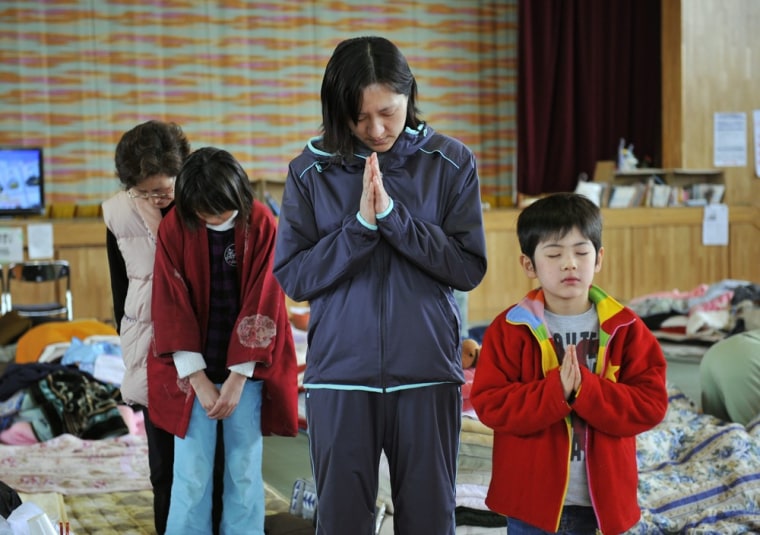 Image: A family offers a silent prayer for tsunami victims