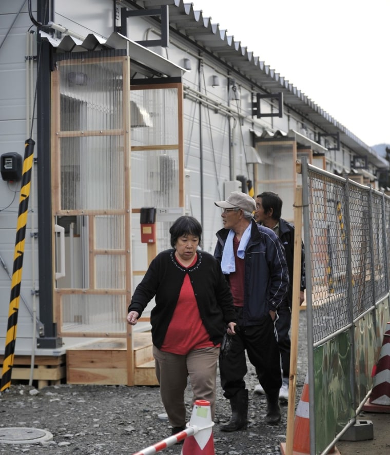Image: Evacuees walk in front of their temporary housing