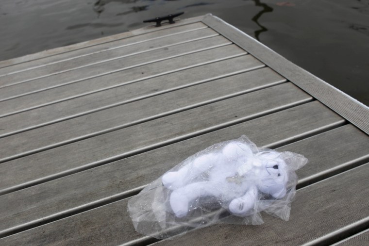 Image: A teddy bear wearing a cross is seen next to the boat ramp where a woman drove her minivan into the Hudson River in Newburgh, N.Y