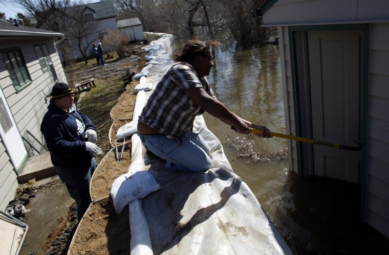Image: Resident Russell Lee watches as Trina Lee tries to close the door to their garage behind their home in Valley City, North Dakota