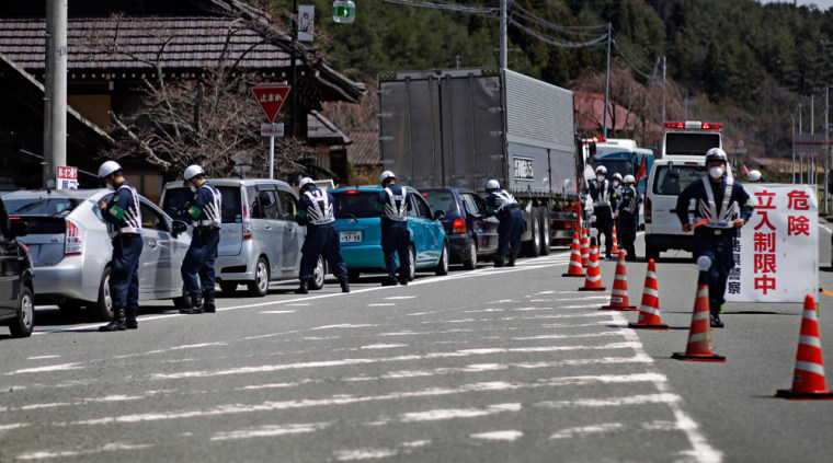 Image: Police officers stop cars at a checkpoint near the town of Namie, inside the 20-kilometer (12-mile) evacuation zone, in Fukushima Prefecture, northeastern Japan
