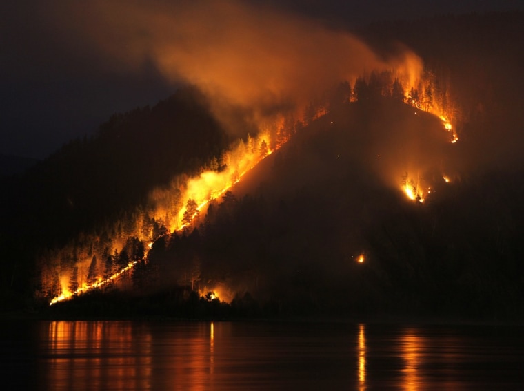 Image: Dry grass, bushes and trees burn on the bank of the Yenisei River in Taiga district