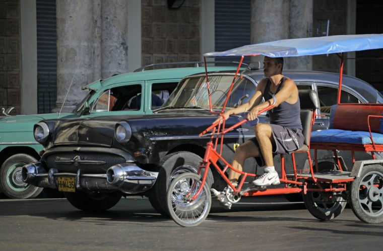 Image: A man looks for customers on his tricycle taxi in Havana