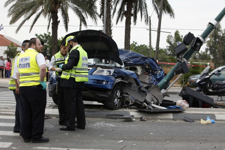 Image: Israeli rescue workers stand at site where truck slammed into vehicles in Tel Aviv