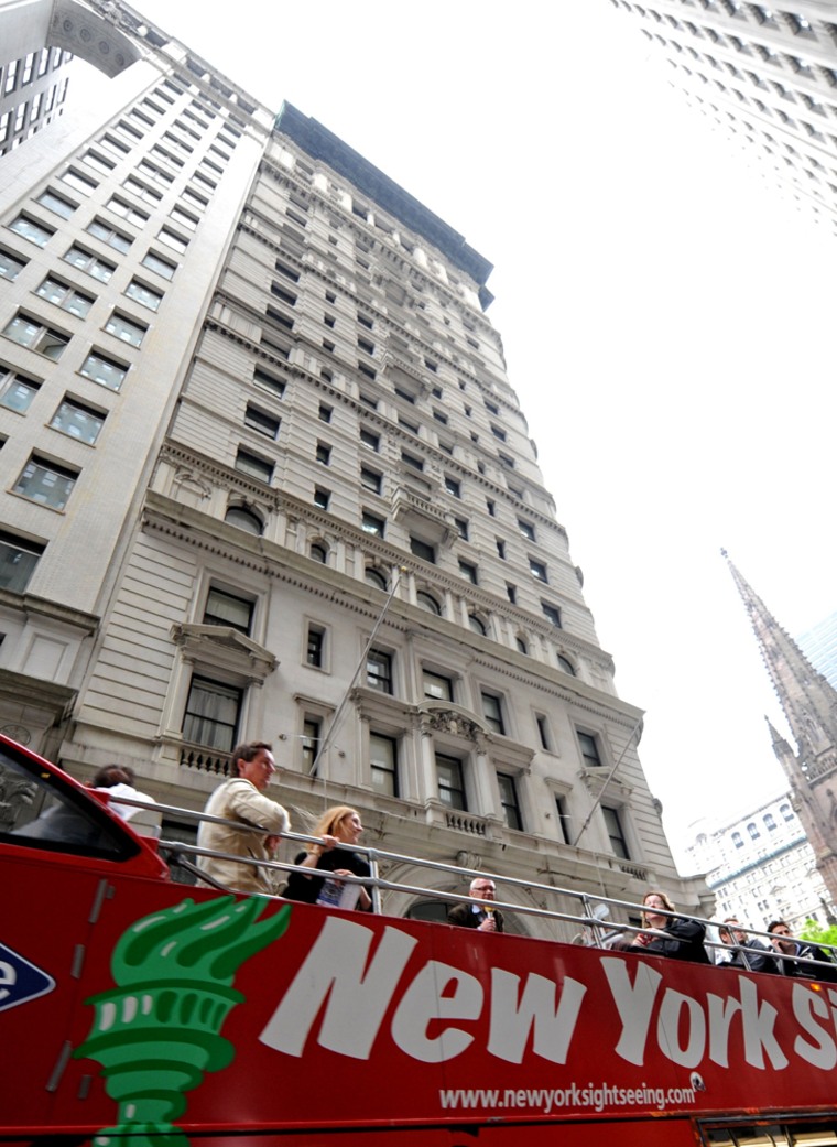 Image: A sightseeing bus drives past the building where former IMF head Dominique Strauss-Khan is being held under house arrest after posting bail, in New York