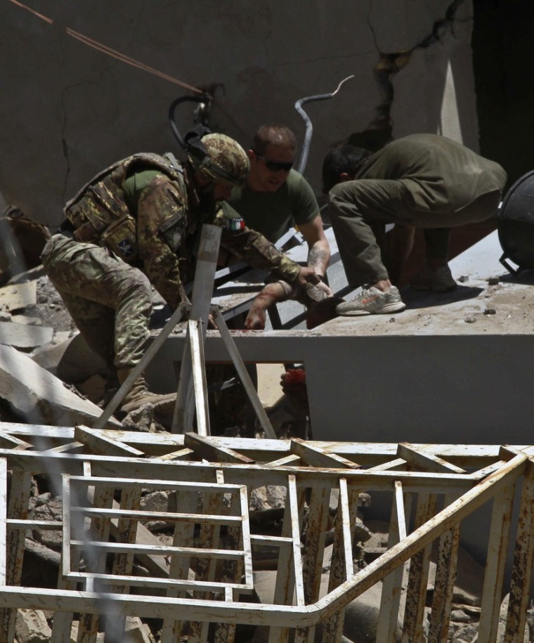 Image: An Italian soldier helps a wounded person after a blast near a foreign base in Herat
