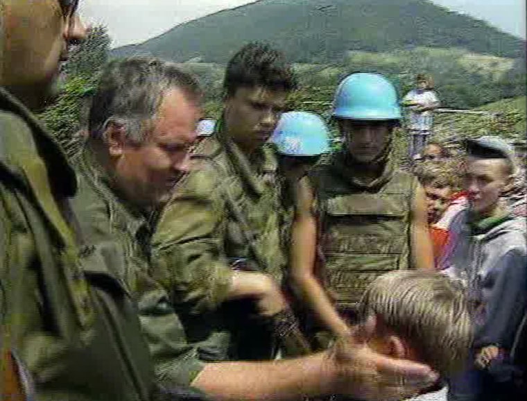 Image: Bosnian Serb boy Izudin Alic being patted on the head by a grinning Ratko Mladic in 1995