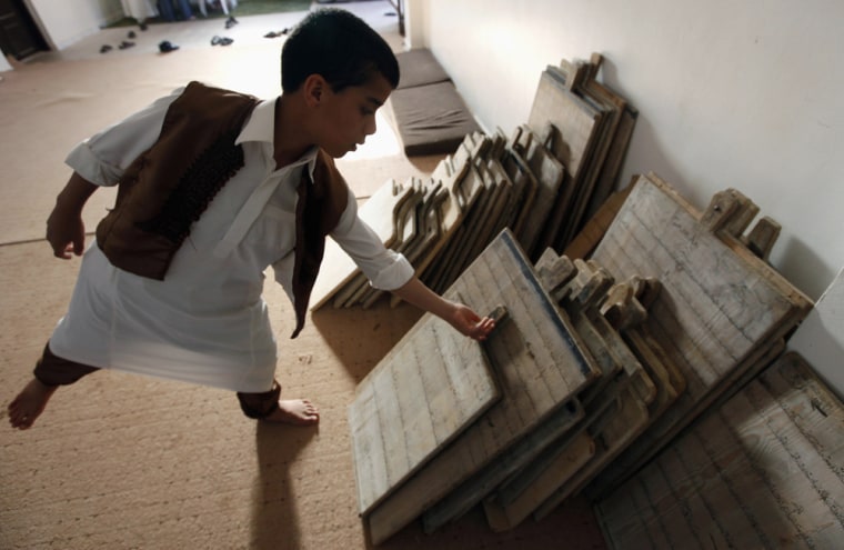 Image: A Libyan boy takes a wooden slate which he uses to practice memorizing the holy Koran, at a school in Benghazi