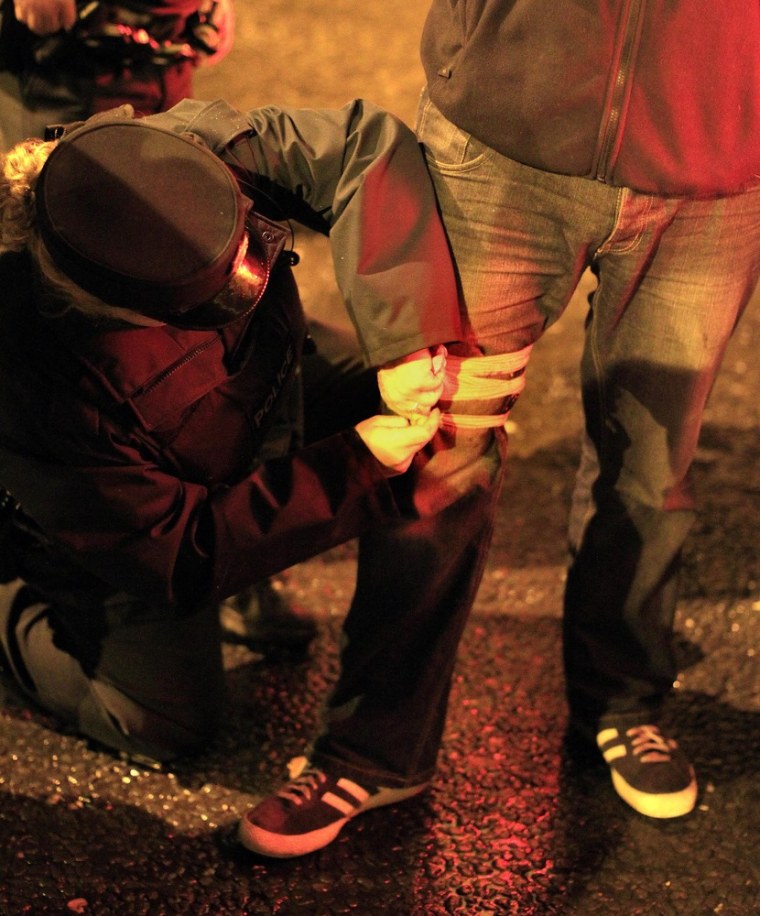 Image: A Northern Ireland police officer puts a bandage on a press photographer's leg after he was shot by a rioter