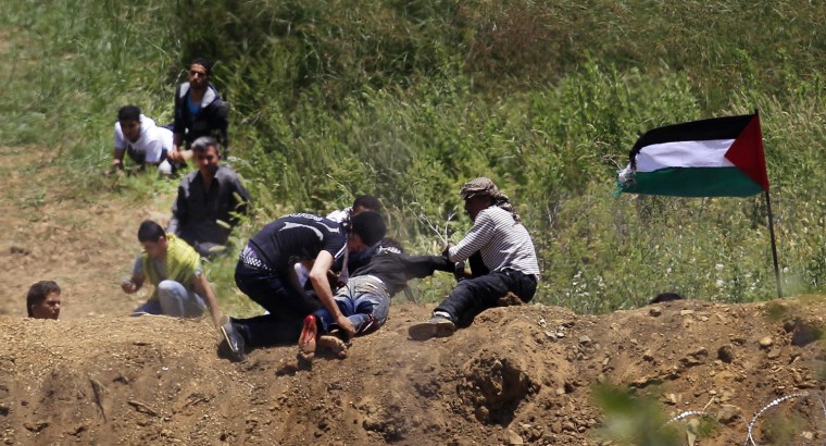 Image: A wounded protester is dragged away from the Syrian-Israeli border near Majdal Shams in the Golan Heights